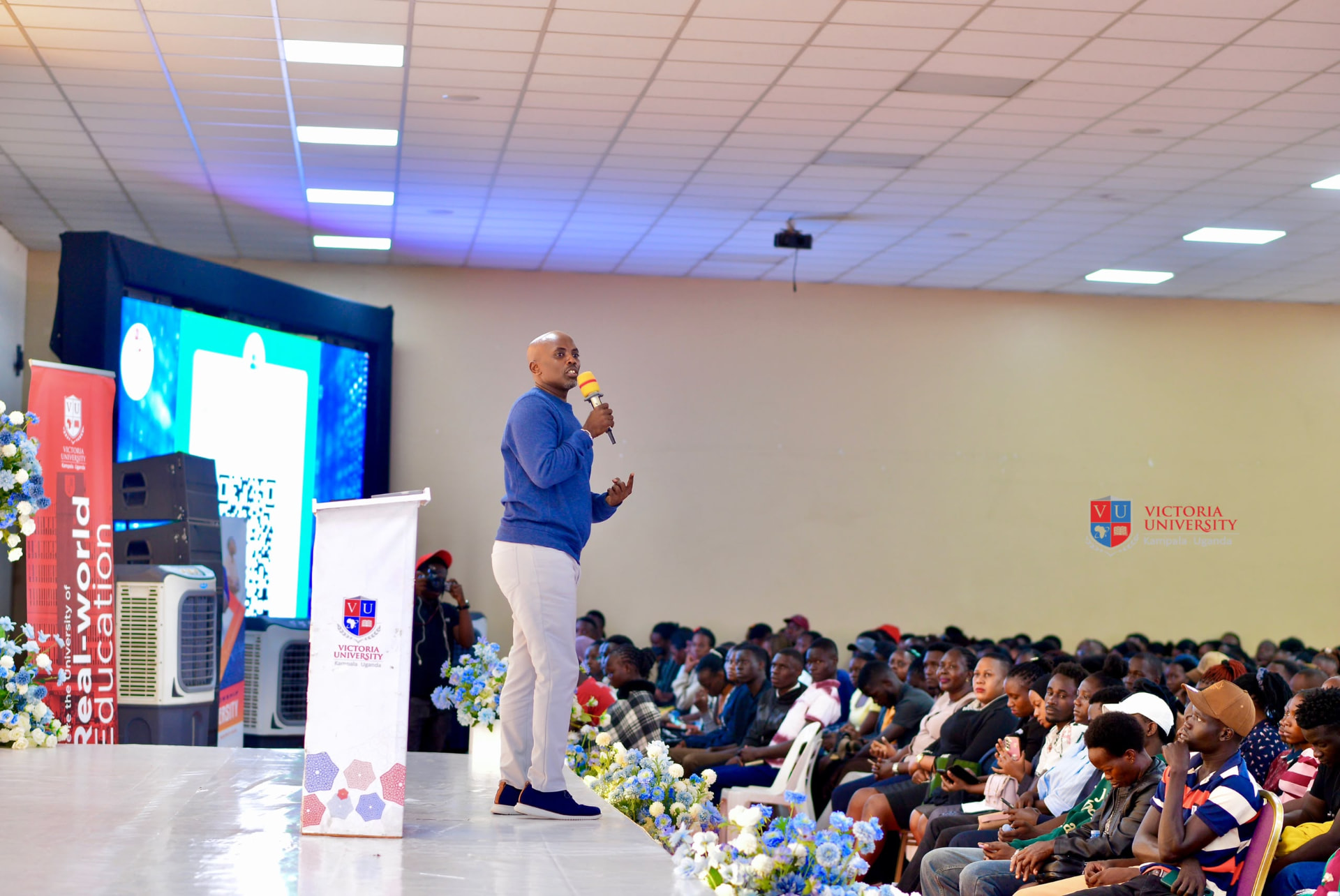 Victoria University leadership addressing a packed hall of students in Kampala